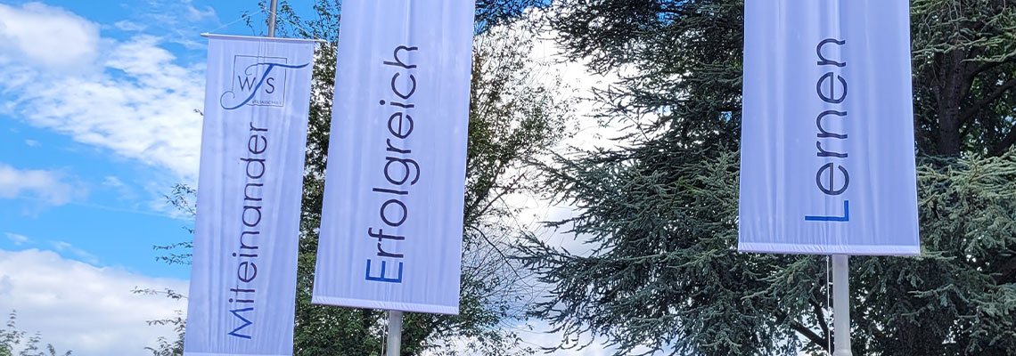 Foto von Fahnen der Weiltalschule am Eingang.